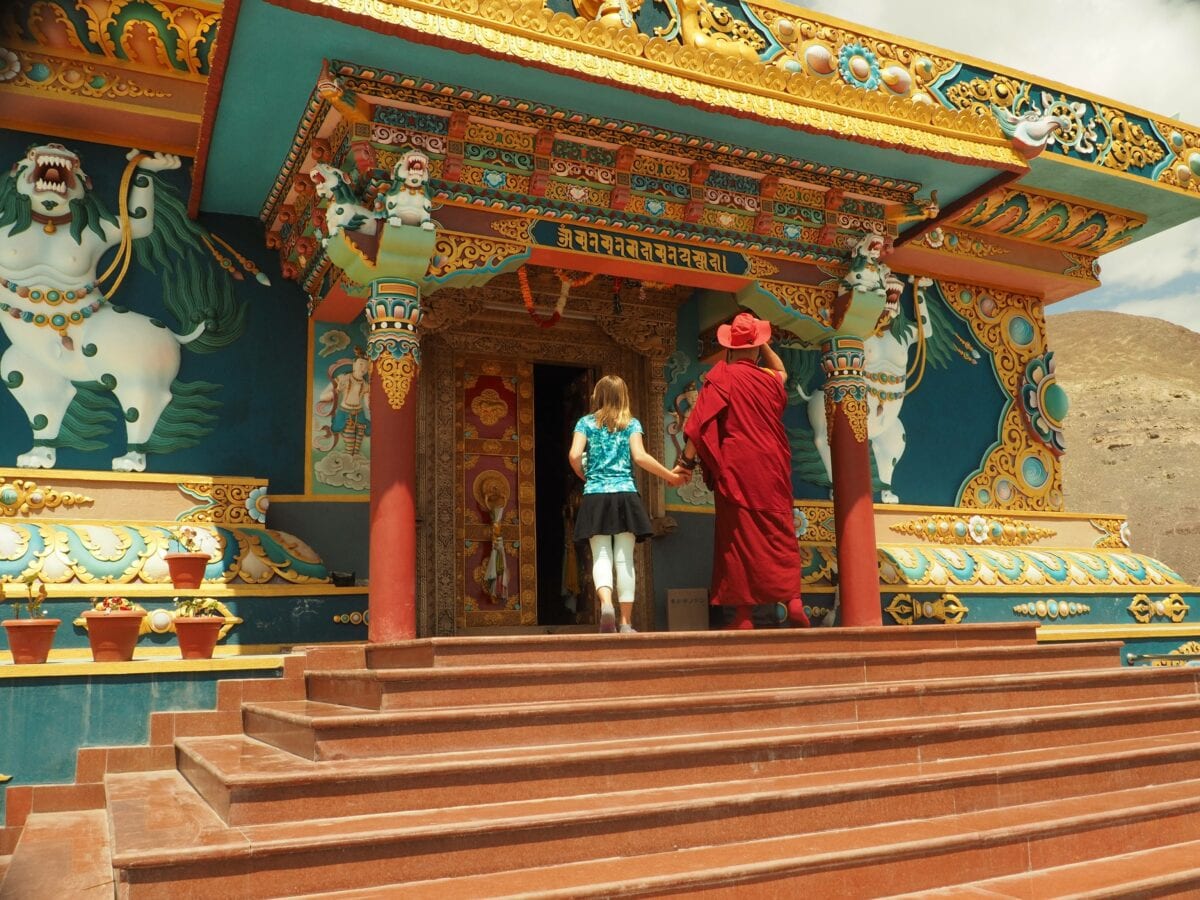 Girl holding hand of someone walking into the Monastery-of-Big-Buddha-in-Stok-Ladakh - volunteer family travel to India - A Magical Family Adventure in India