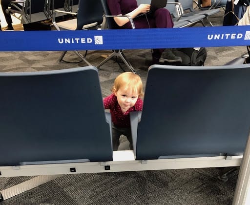 baby peeking out between two seats - Flying with a Baby for the first time