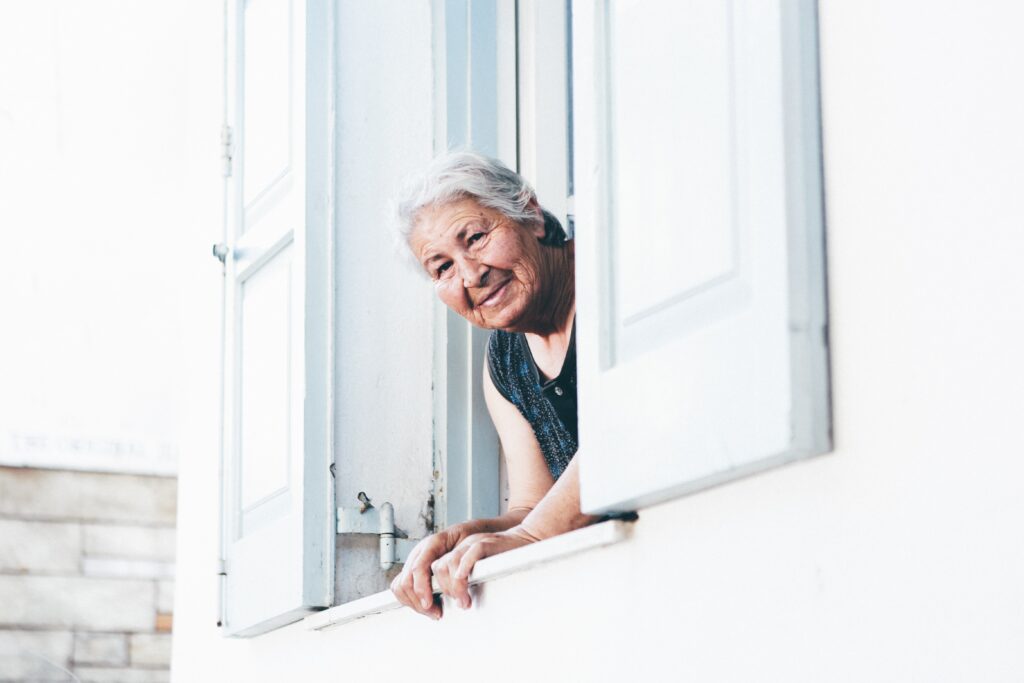 women peaking out her window - Travel In Time: Tips to Help the Elderly Cope with Coronavirus