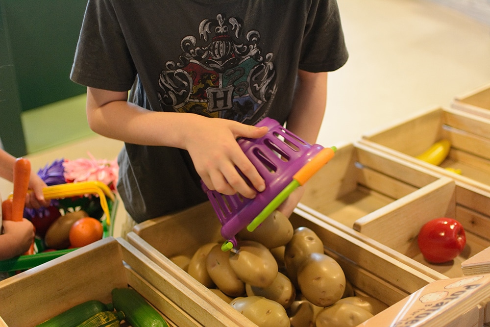 kid with fake produce - 7 Essential Stops on a Family Summer Texas Road Trip