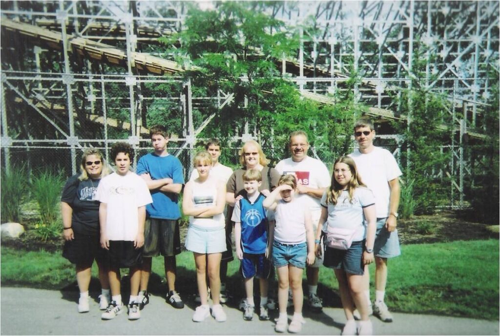 Family Photo in front of Roller Coaster - The Only Things You Need to Pack in a Theme Park Bag