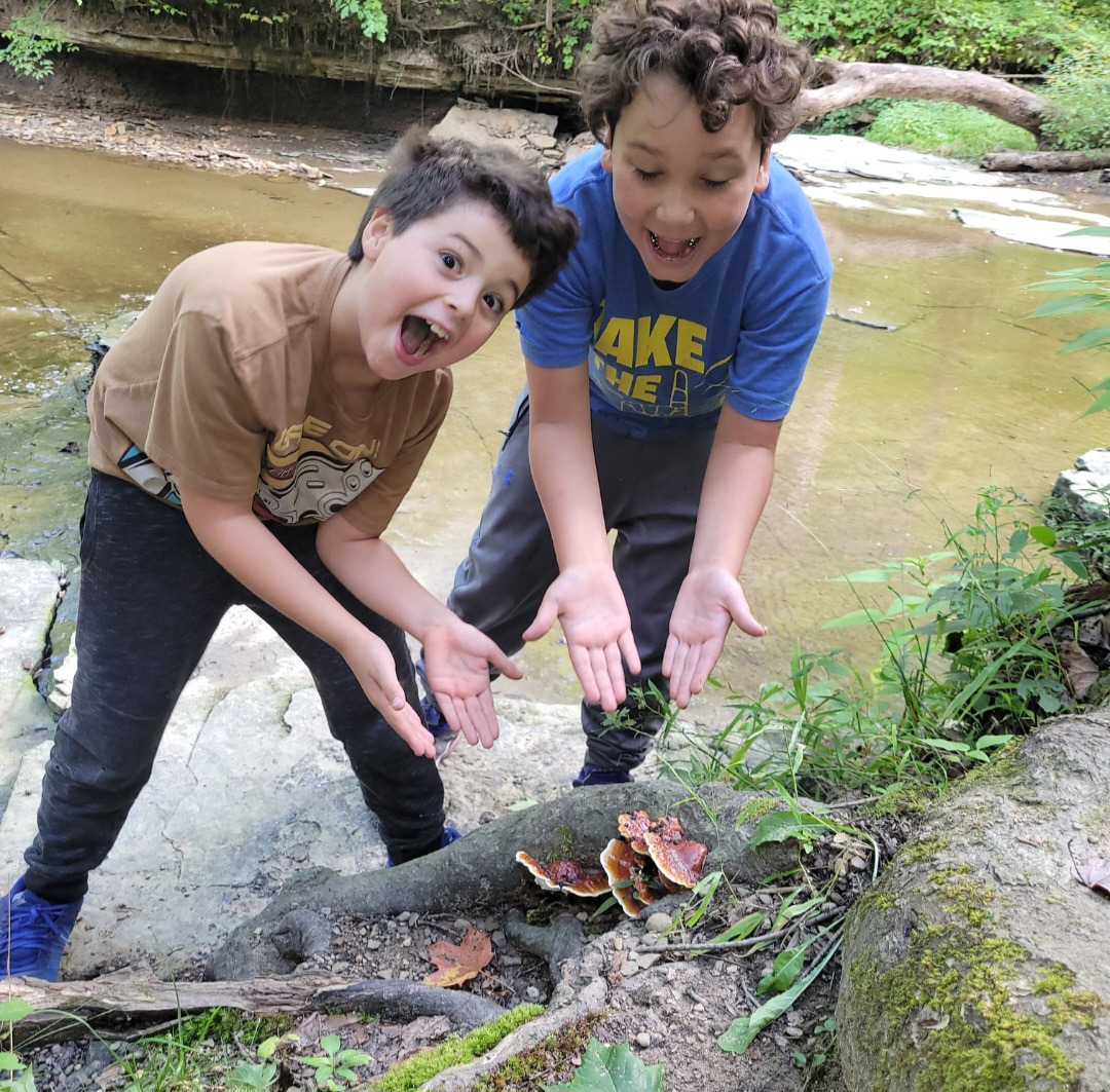 Two boys making funny faces and gesturing to mushrooms. Best things to do in Cleveland, OH with kids. 