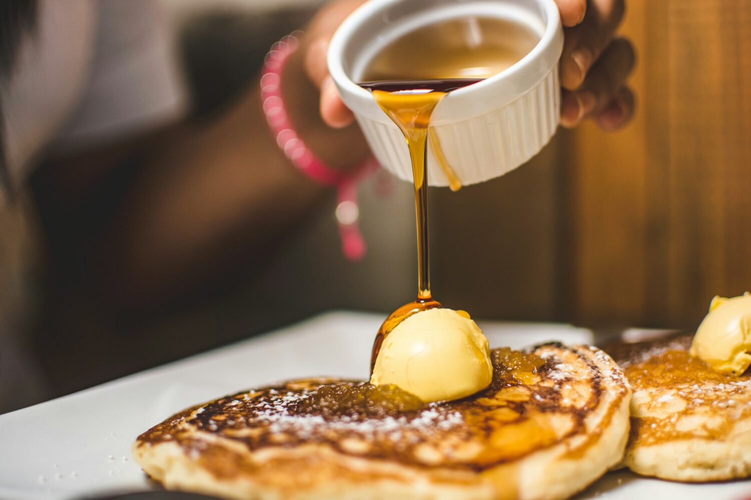 Maple syrup being poured over a stack of pancakes with butter. Things to do in Cleveland, OH with kids.