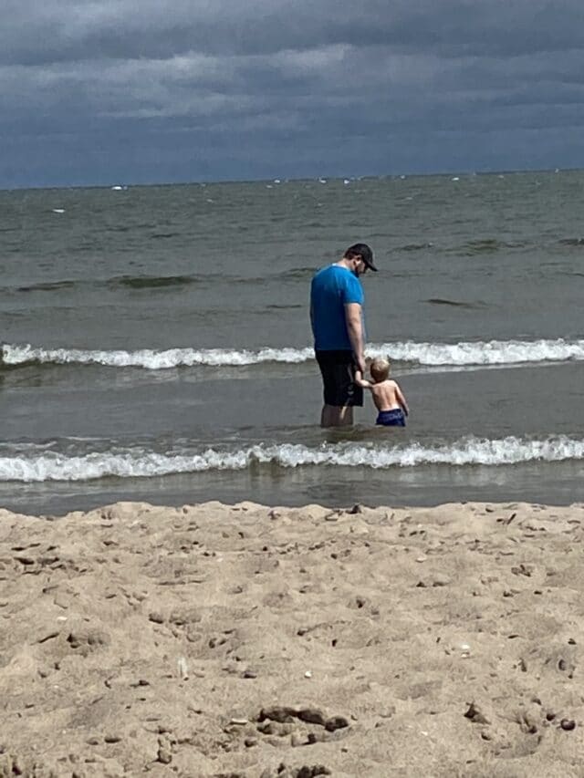 Photo of toddler and dad in the water at the beach