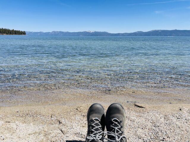 Boot-clad feet shown with the backdrop of Lake Kiva, a clear blue color.7 Not To Miss Things To Do In South Lake Tahoe With Kids family travel