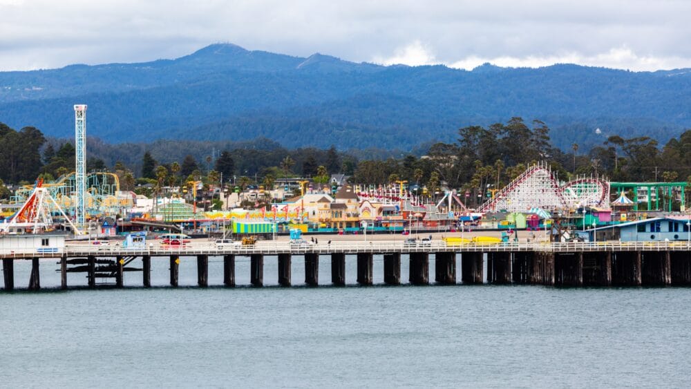 Santa Cruz Boardwalk, shown from the ocean, with mountains in the background. Best things to do with kids in Santa Cruz family travel 