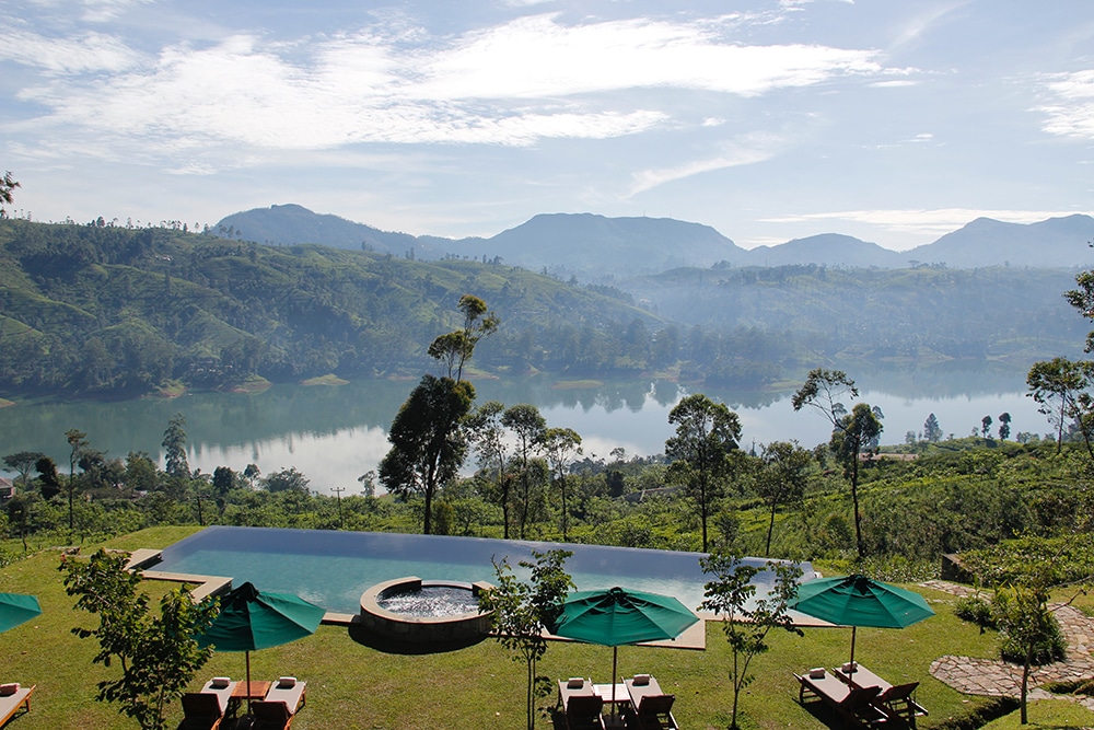 A resort pool with umbrellas and beach chairs, with a blue lake and mountains in the background. Get away to a resort for Labor Day fun.