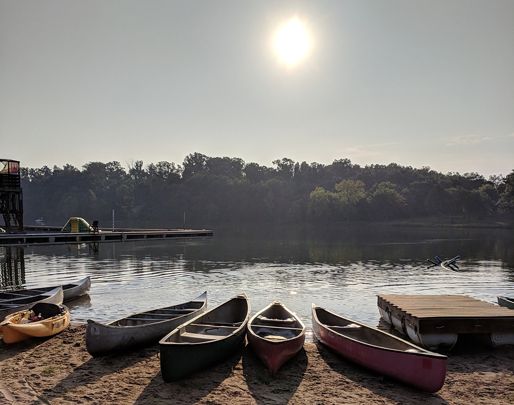 Empty canoes on the edge of a lake at sunrise. Plan an outdoor adventure for Labor Day fun. 