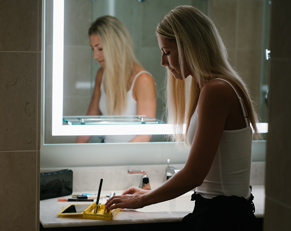 Travel hacks for moms: A mom does her makeup at a hotel mirror. No kids in sight.