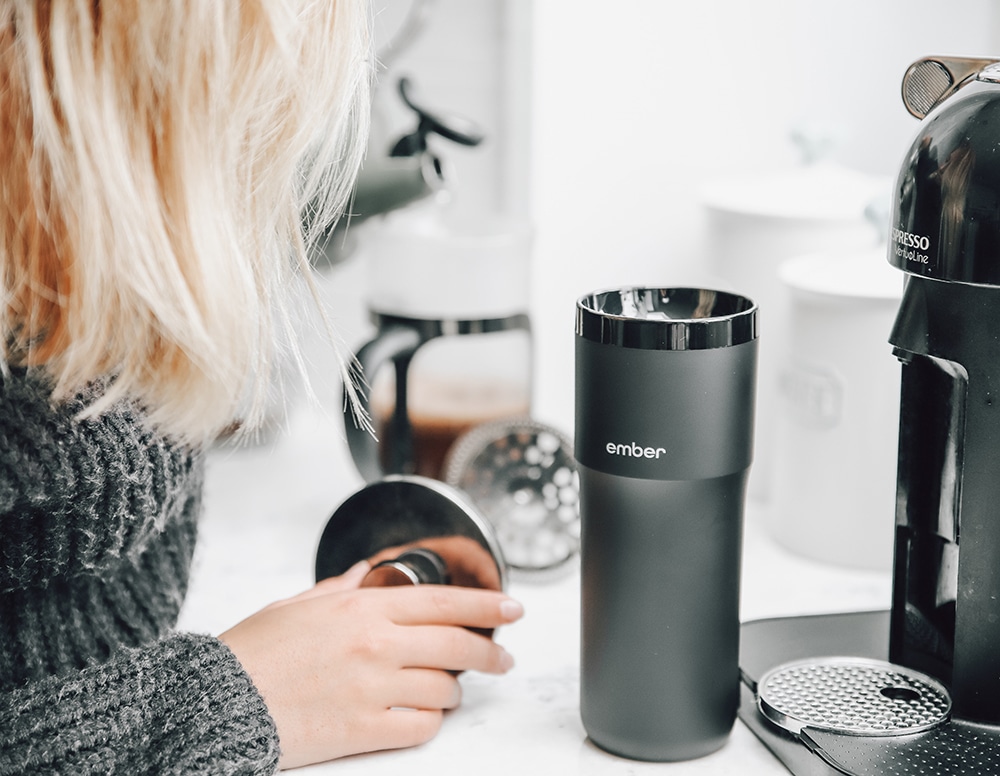A woman makes coffee to go in her travel mug. Mom Travel Hacks.