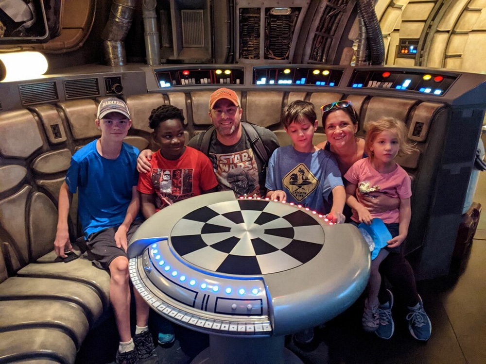 A family sits in the Millenium Falcon at Disneyland during their family vacation. Parents can work together to help kids with anxiety when traveling.