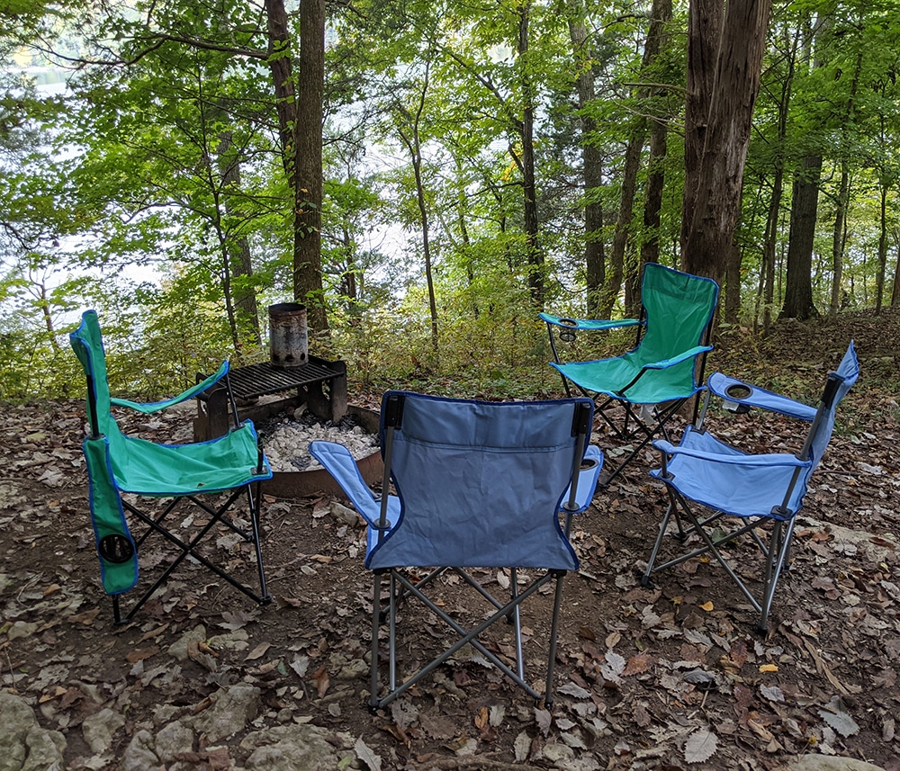 Chairs in a circle around a firepit. Tent camping for beginners. 