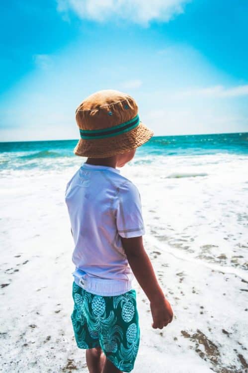 A young boy looking over the white sandy beaches into the clear blue