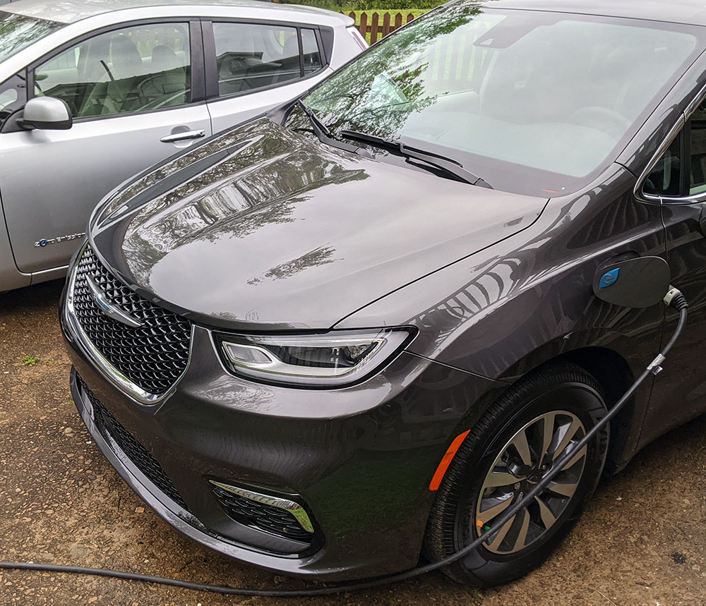 A back plug-in hybrid vehicle being charged - Tips for Taking a Family Road Trip with an Electric Vehicle