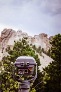 A view of Mt. Rushmore through a set of observation binoculars.// Presidents Day Weekend Trips: Learning Vacations For Families