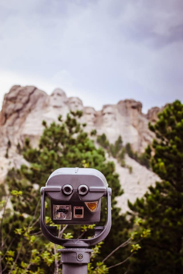 A view of Mt. Rushmore through a set of observation binoculars.// Presidents Day Weekend Trips: Learning Vacations For Families