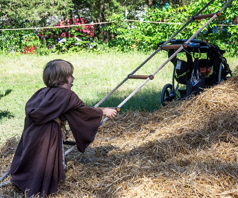 A boy in brown robes climbs a rope ladder at the Tennessee Renaissance Festival. 