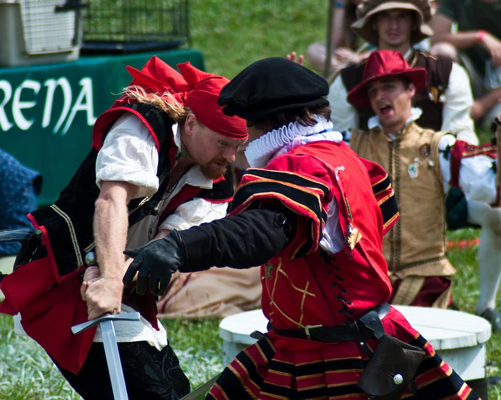 Two actors in Renaissance garb fight with swords at the Tennessee Renaissance Festival