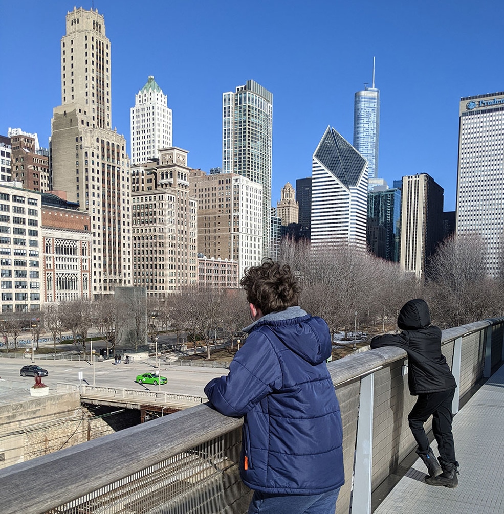 Two kids stand on a bridge and look at Chicago's skyline