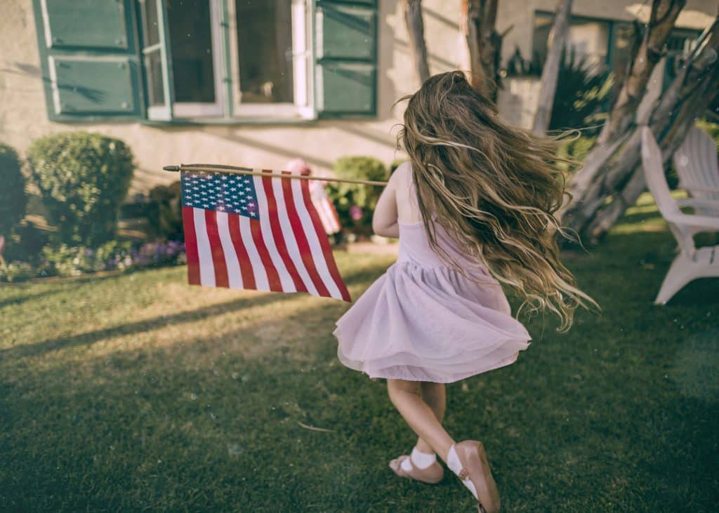 Girl waving flag - The BEST 4th of July Getaways With Kids