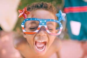 happy child with patriotic glasses - The Best 4th of July Getaways With Kids