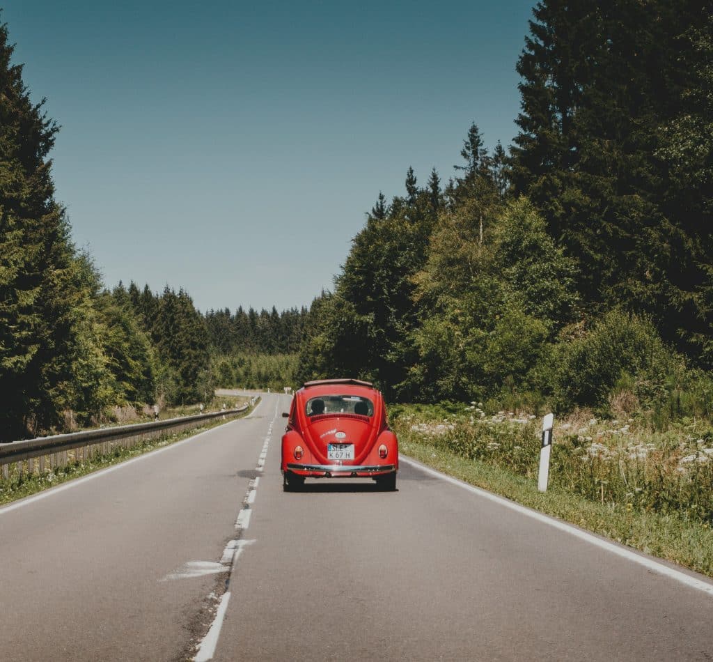 A red VW bug on the highway during a road trip. Punch Buggy.