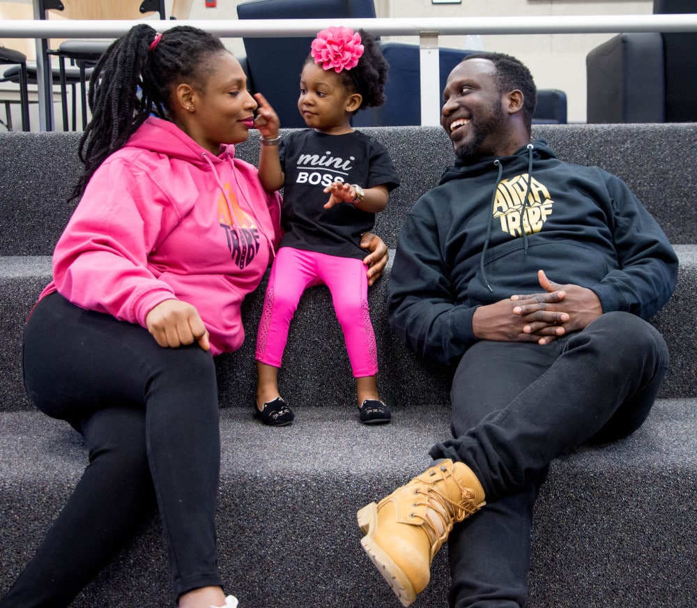 Two parents sit with their preschooler, who is wearing a shirt that says "Mini Boss."