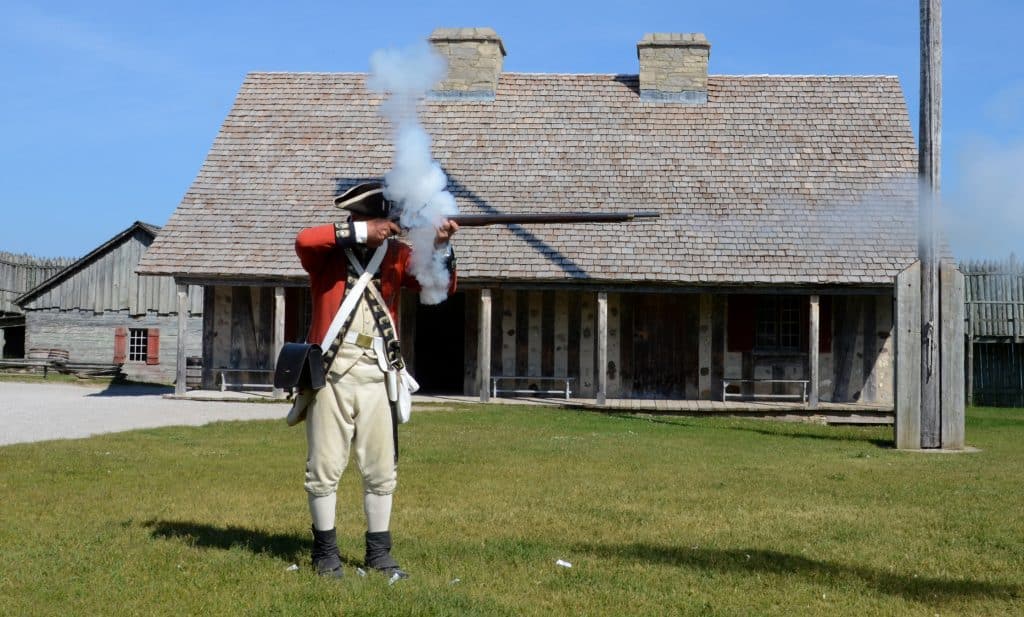 A re-enactor demonstrates how to fire a musket at Colonial Michilimackinac