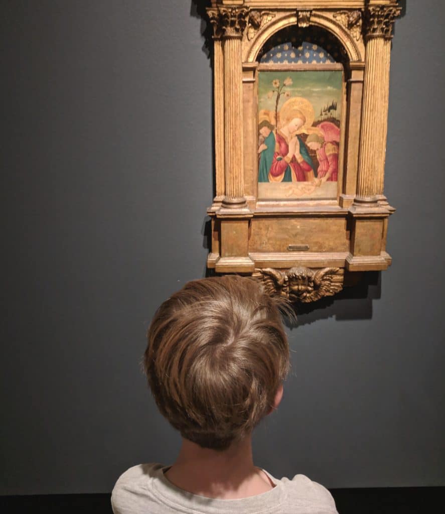 A child looks at a Renaissance painting in an art museum. 