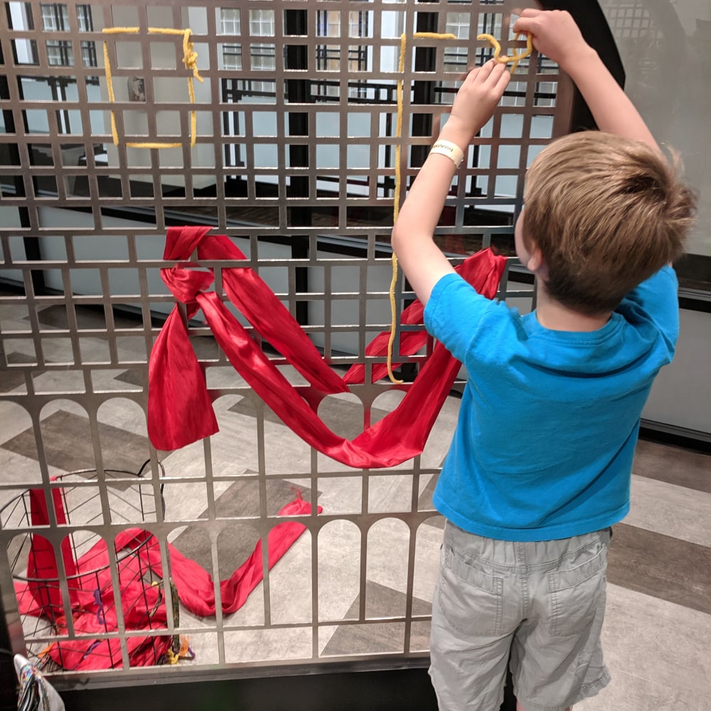 A child weaves a giant ribbon at an art museum kids area