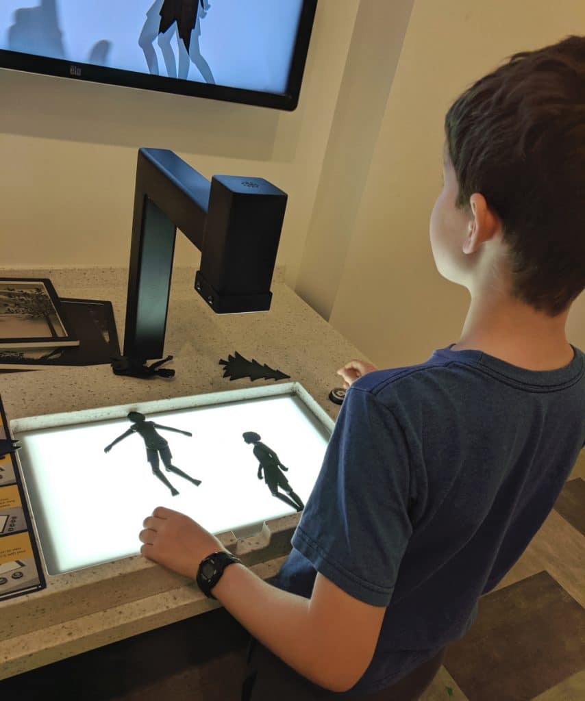 A tween boy works on a stop-motion animation project in the children's area of an art museum. 