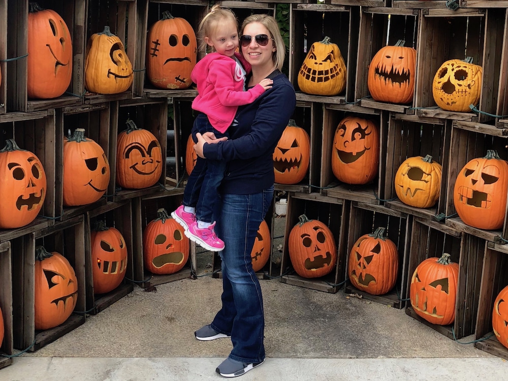 jack o' lanterns in crates with woman holding child in front - best fall destinations in the US