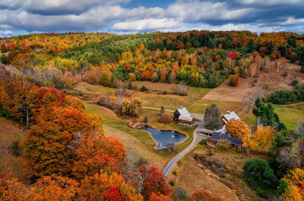 fall foliage around a barn - best fall vacations in the usa