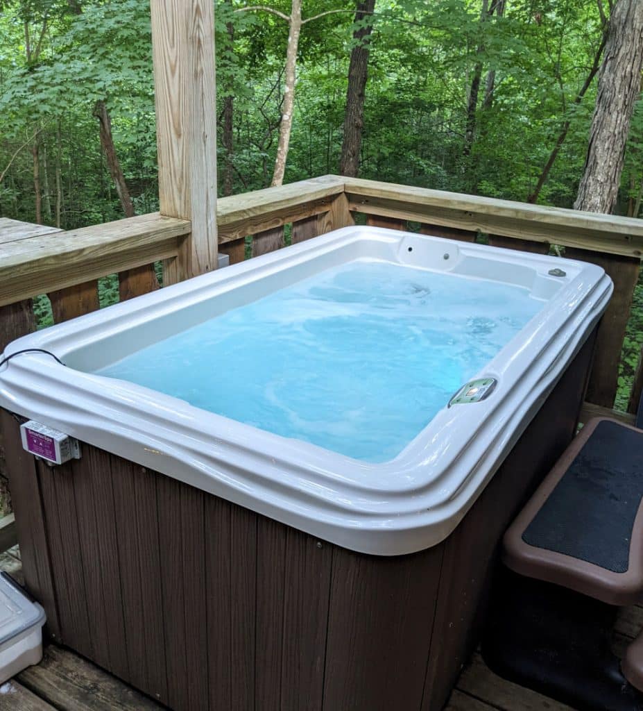 A saltwarer hot tub with a backdrop of green trees