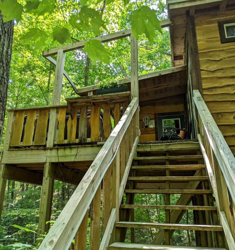 Wooden stairs leading up to the back deck and hot tub of the treehouse