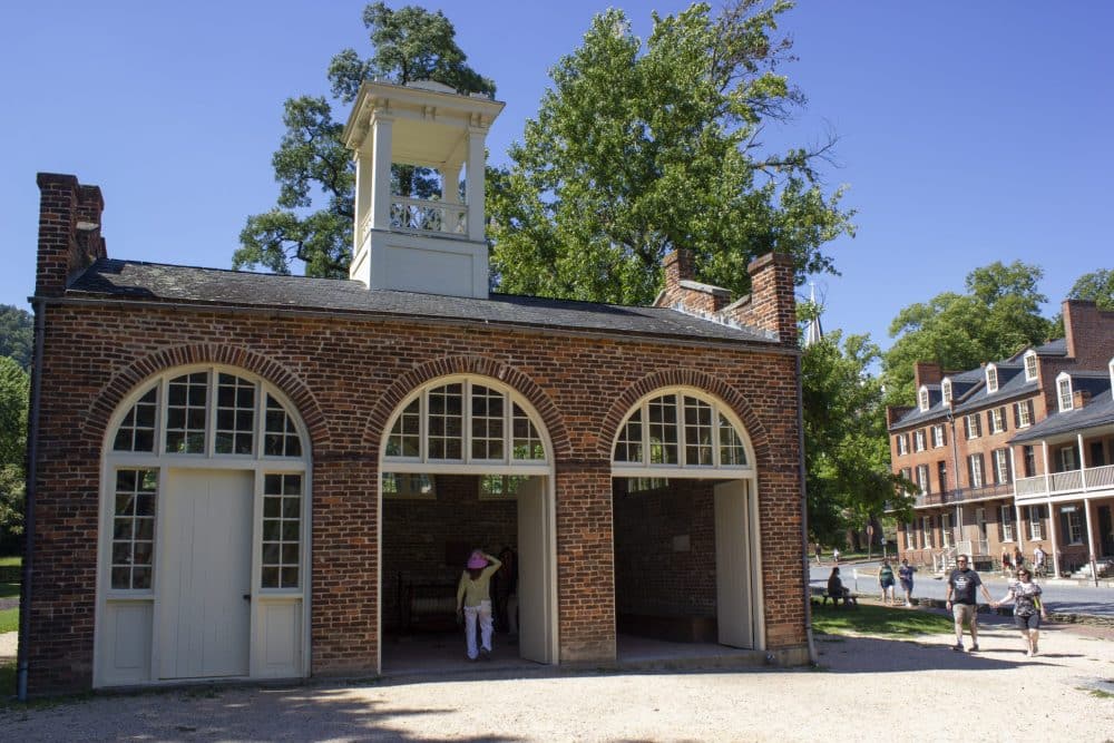 Historic brick building with person walking through open door.