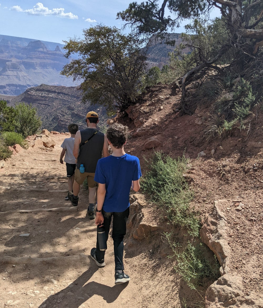 Two kids and dad walking down stone canyon steps - Grand Canyon With Kids 