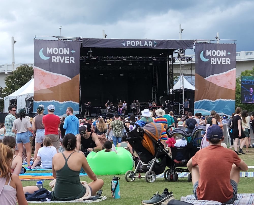 Crowds, including a child in a stroller, wait for the next performance at Moon River Festival.