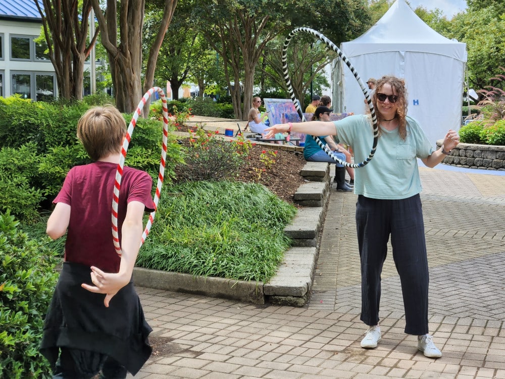A woman and her tween son hula hoop together at Moon River Festival.