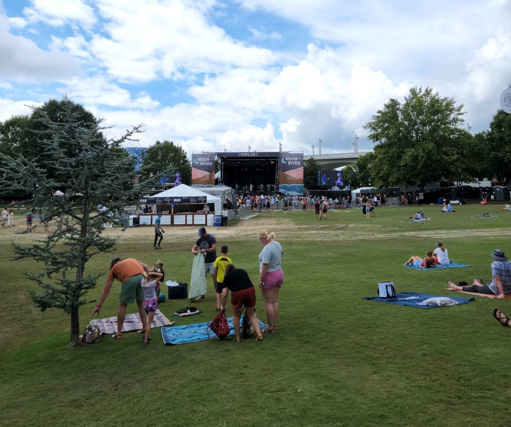 A family sets up blankets on the grass at the Moon River Festival.
