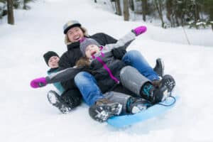 A Father and daughters sledding at winter time in montreal, canada