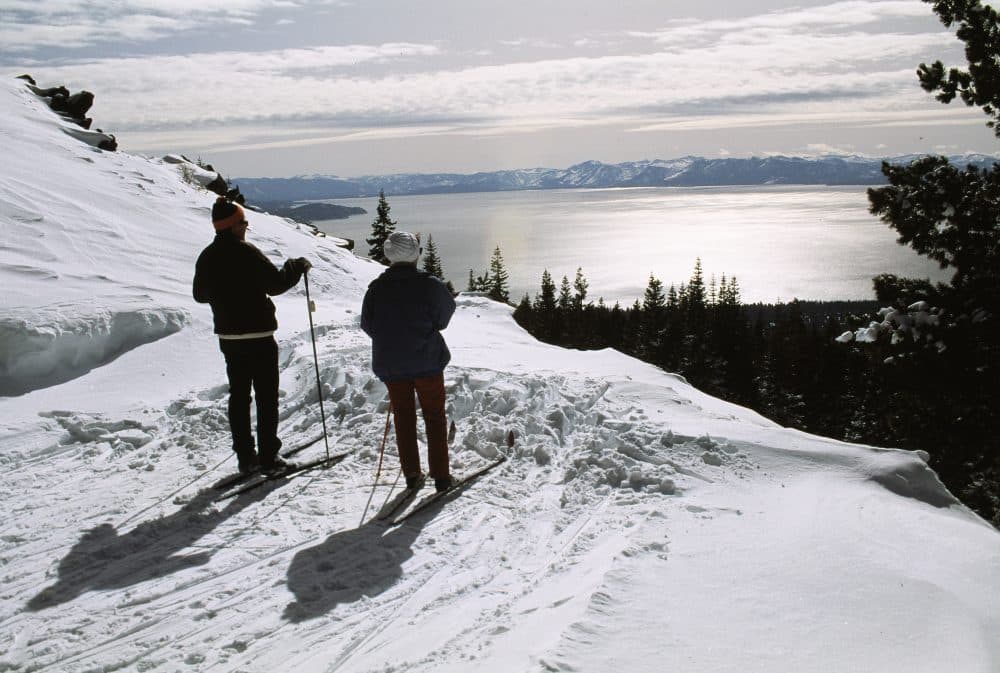 Two cross-country skiers look out over Lake Tahoe from their snow covered mountainside position near Mount Rose highway on the North Shore