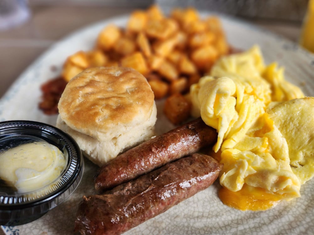 A breakfast plate with sausage, eggs, hashbrowns, and a biscuit at Rita's Seaside Grill in Folly Beach