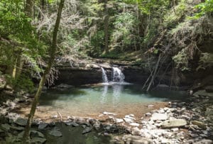 A small waterfall emptying into a blue swimming hole in South Cumberland State Park near Monteagle, Tennessee