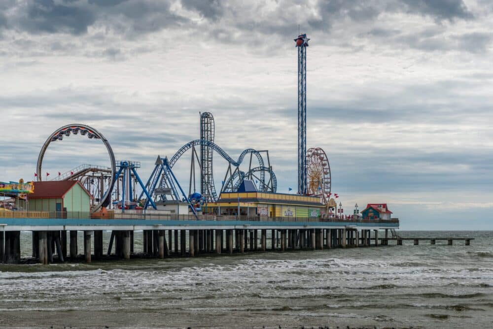 An amusement park on a pier jets out into the water. Best Beaches in Galveston For Families