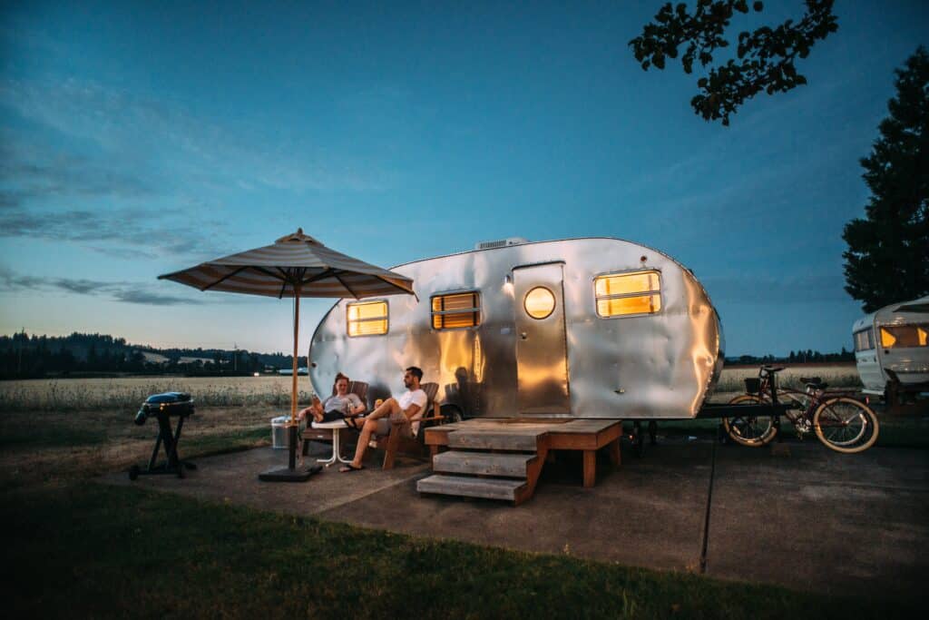 two people in front of an airstream trailer - best small travel trailers for families of four 