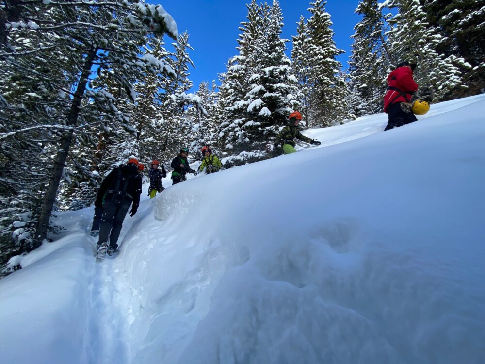 people trudging uphill through snow - What To Do In Big Sky Montana