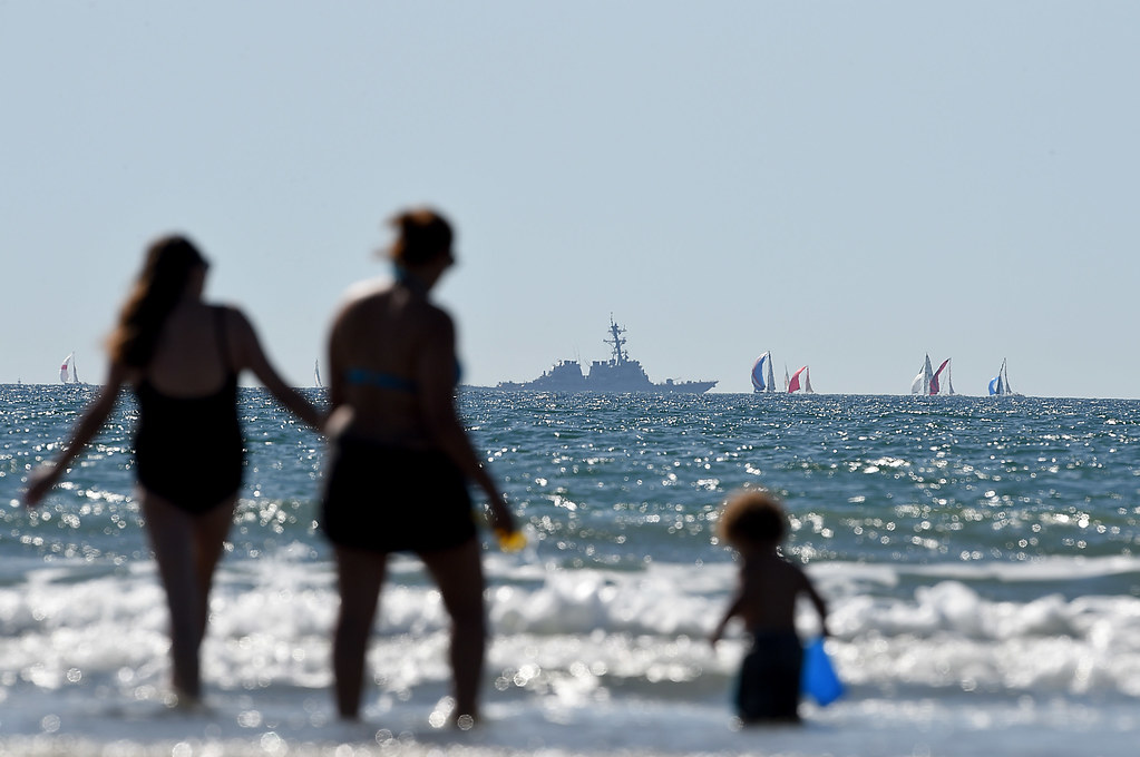 Family playing on the beach with battleships in background - 5 Best Charleston Beaches for Epic Family Vacations