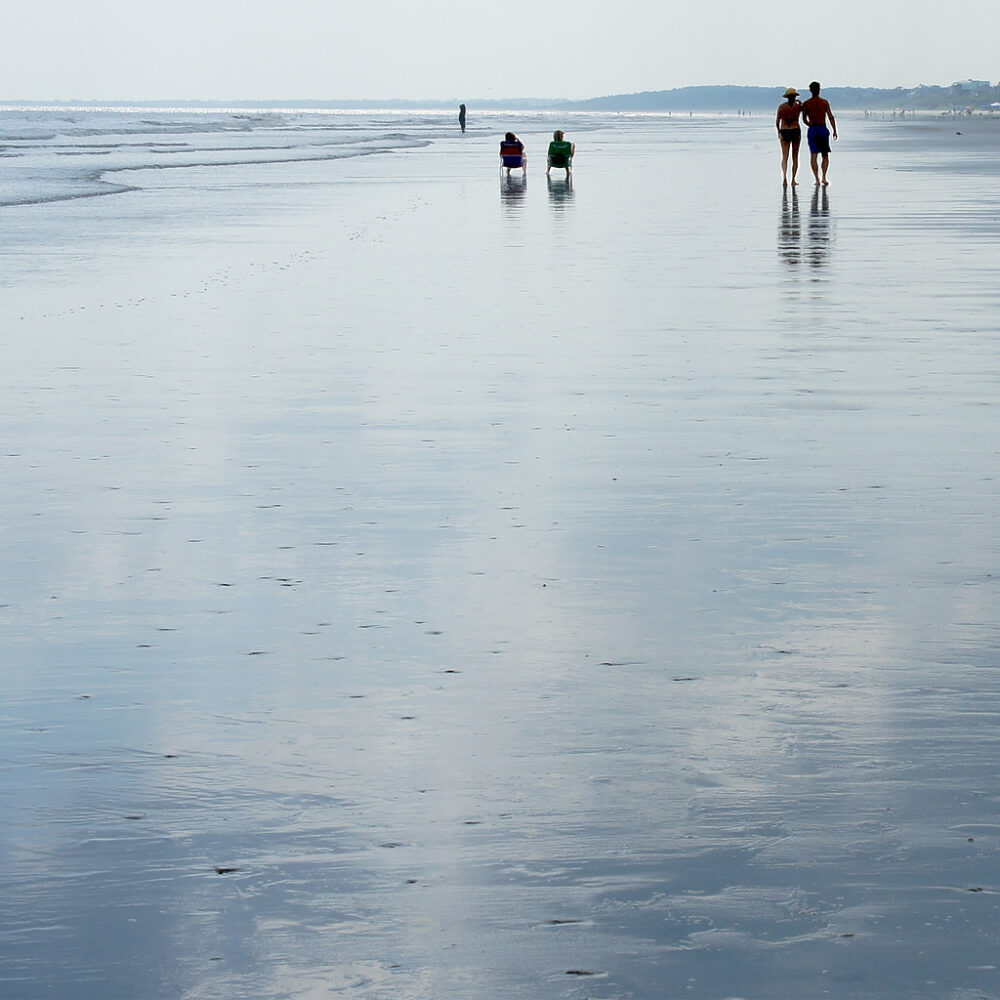 Five people walking and sitting on the Kiawah Island beach - 5 Best Charleston Beaches for Epic Family Vacations
