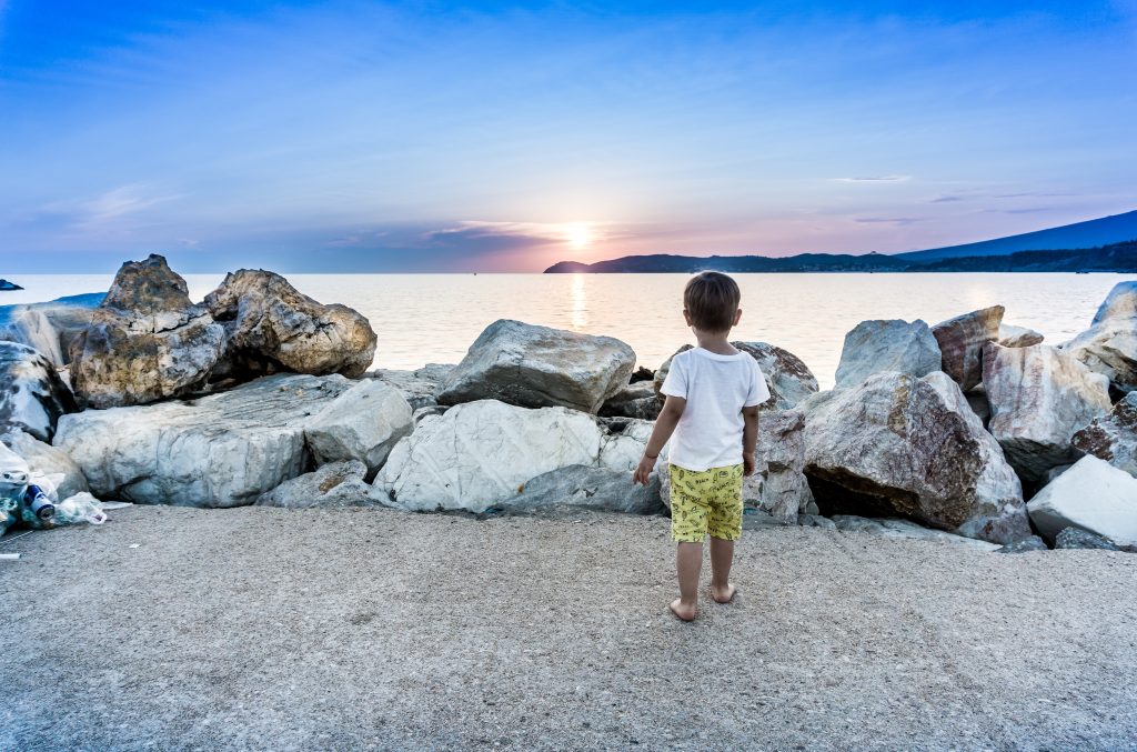 boy by rocks and water - Europe family vacations